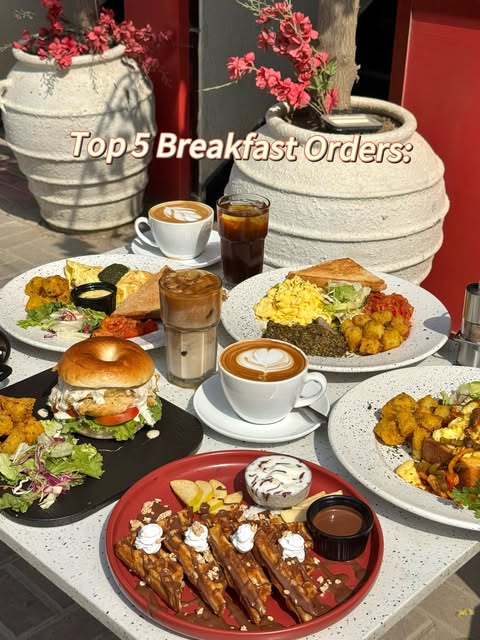 A Florentine breakfast spread: eggs, waffles, a bagel sandwich, iced coffee and lattes on a terrazzo table